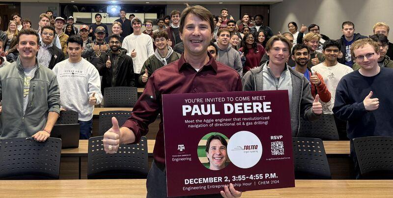 Speaker Paul Deere holding his Engineering Entrepreneurship Hour poster in front of a room of students
